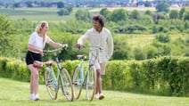 Two guests walk along beside their Pashley bikes in the grounds of Studley Castle Hotel