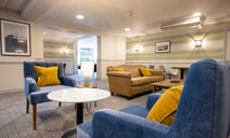 The lounge area featuring blue chairs adorned with yellow pillows, creating a vibrant and inviting atmosphere.