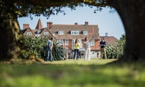 People engaged in a game of pitch and putt, with Bembridge House in the background.