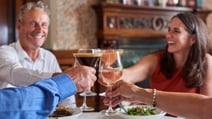 A joyful group toasting with wine glasses at Brasserie32 in Heythrop Park, celebrating together in a vibrant atmosphere.