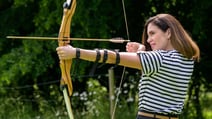 A woman targets her shot with a bow and arrow at Heythrop Park, demonstrating skill and concentration in archery