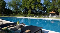 The outdoor pool at The Runnymede on Thames Hotel, featuring a sun lounger and a cocktail that has been brought over from the Lounge bar