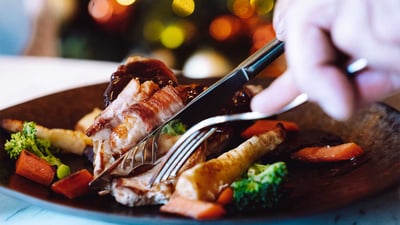 Image of someone cutting meat with a knife on a plate.