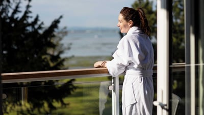 A woman in a robe enjoying the view of the water during a singles break at Warner Hotel.
