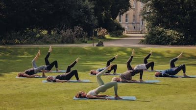 Guests perform a yoga pose during a wellness retreat workshop at Heythrop Park