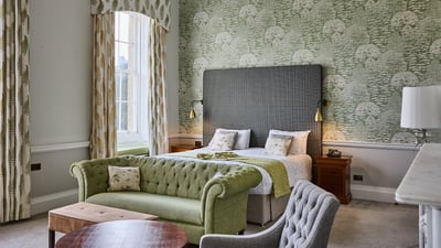 A cozy hotel room with a vibrant green couch and a comfortable bed, perfect for a relaxing stay.