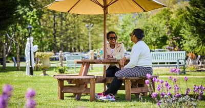 Two women enjoying a picnic at Sinah Warren, surrounded by nature's beauty. Relax, bond, and create memories in the great outdoors.