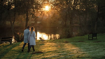 A couple walking beside a lake at Gunton Hall