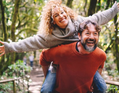 A man and woman share a smile while riding along a picturesque trail at Warner Hotels.