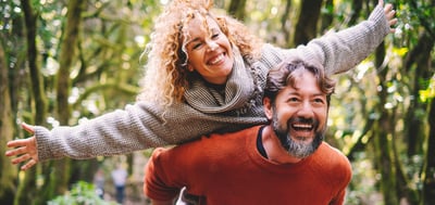 A man and woman share a smile while riding along a picturesque trail at Warner Hotels.