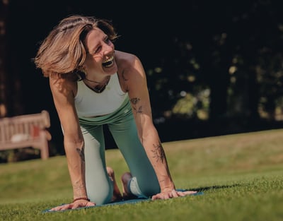 A woman practices yoga on a grassy field