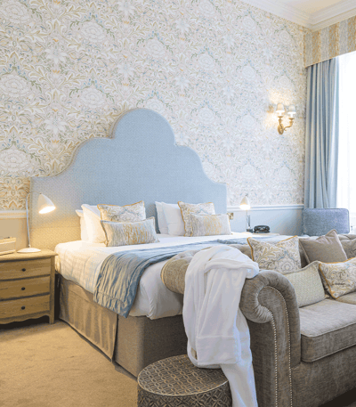 Immerse yourself in comfort at Heythrop Park's Jasmine room. Discover a hotel room with a plush bed, inviting couch, and stylish chair.