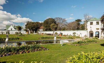 A serene garden featuring a tranquil pond and an elegant fountain, surrounded by lush greenery and vibrant flowers.