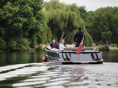 A pair of guests enjoying a boat ride along the River Thames, skippered by a team member at The Runnymede on Thames Hotel