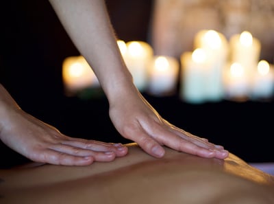 A TEMPLESPA masseuse massages the back of a guest in a darkened candlelit room