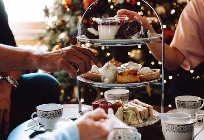 Guests reach for delicious festive treats off of the afternoon tea stand