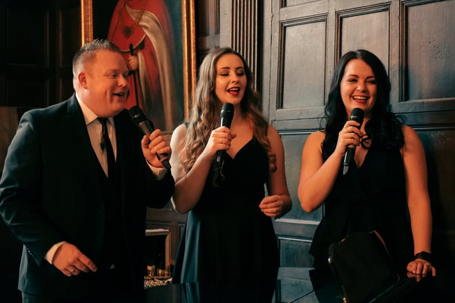 Angie clapping excitedly in the foreground at the entertainment as Mick stares at her lovingly in the background