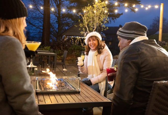 A group of friends enjoying a drink together around the firepit