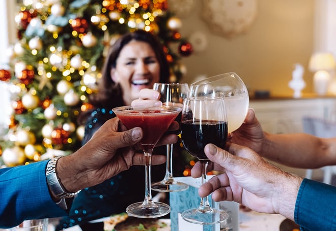 A group of friends make a toast in front of a Christmas tree