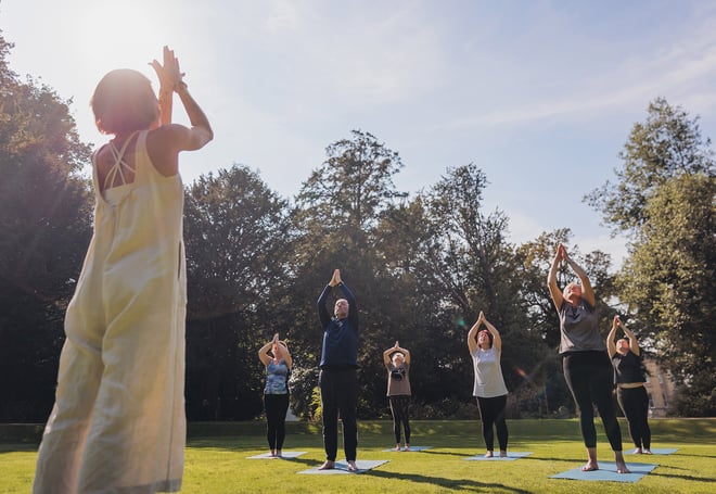 Hotel guests holding a yoga pose during a wellness retreat at Heythrop Park