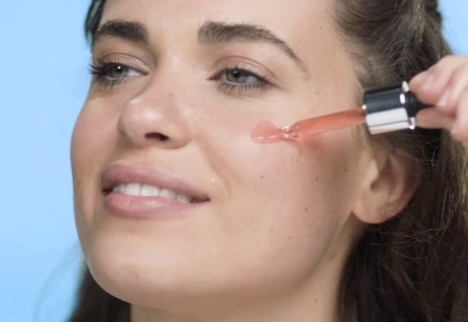 A woman applying serum to her face