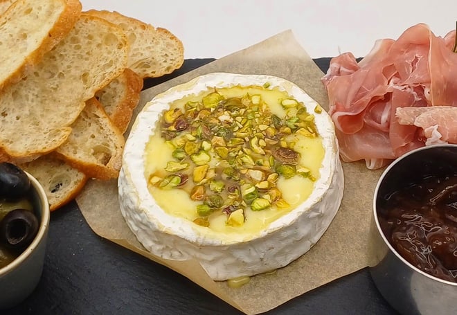 Whole baked Camembert for two: Indulgence at its finest. Enjoy gooey camembert topped with chopped pistachios and a drizzle of honey, served with Prosciutto ham, chutney, olives and toasted ciabatta—a sharing dish that’s as delicious as it is memorable.