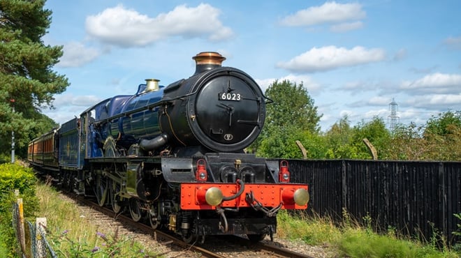 A red steam train on the tracks