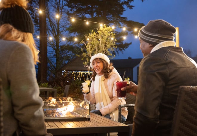 A group of friends enjoying a drink together around the firepit