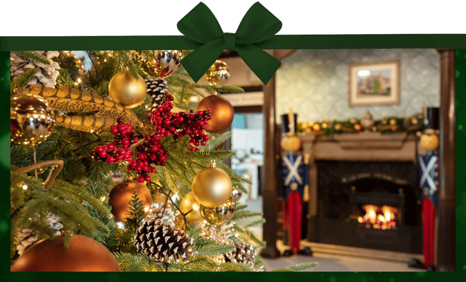 Close up of a Christmas tree with a fireplace in the background and a pair of nutcrackers