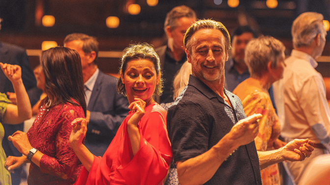 Couple dancing on the dancefloor surrounded by others dancing