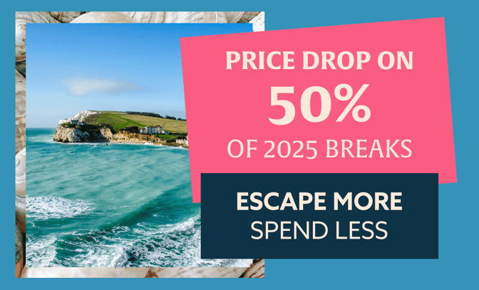 A scenic coastal in Dorset view with text overlay announcing a 50% price drop on 2025 breaks, encouraging to "Escape More, Spend Less."