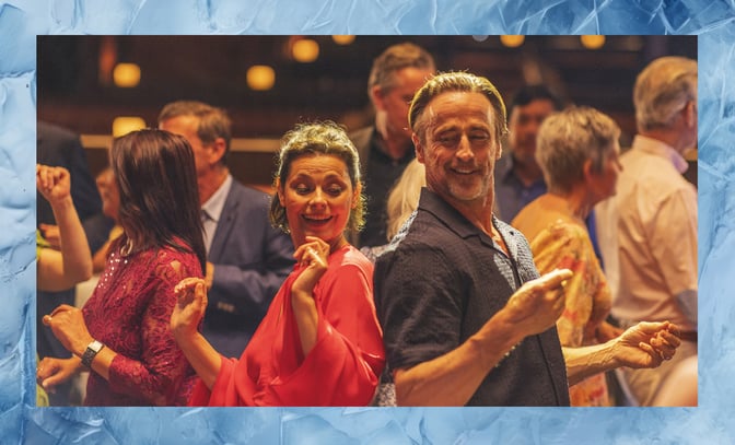 A couple enjoying a dance at a festive party, with smiles on their faces and a vibrant atmosphere around them.