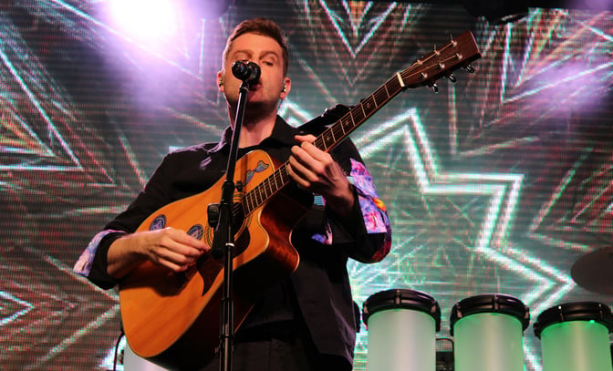 Live in Technicolour performing on stage with a guitar