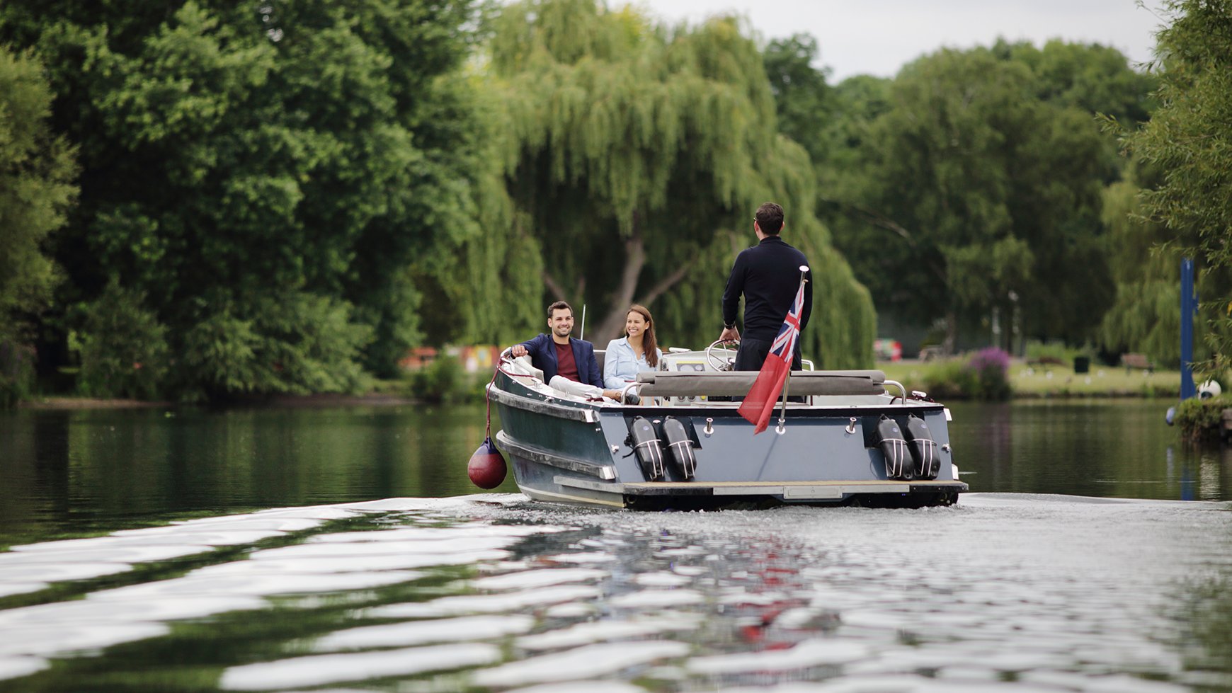 Two guests enjoy a boat cruise as their skipper takes them up the River Thames