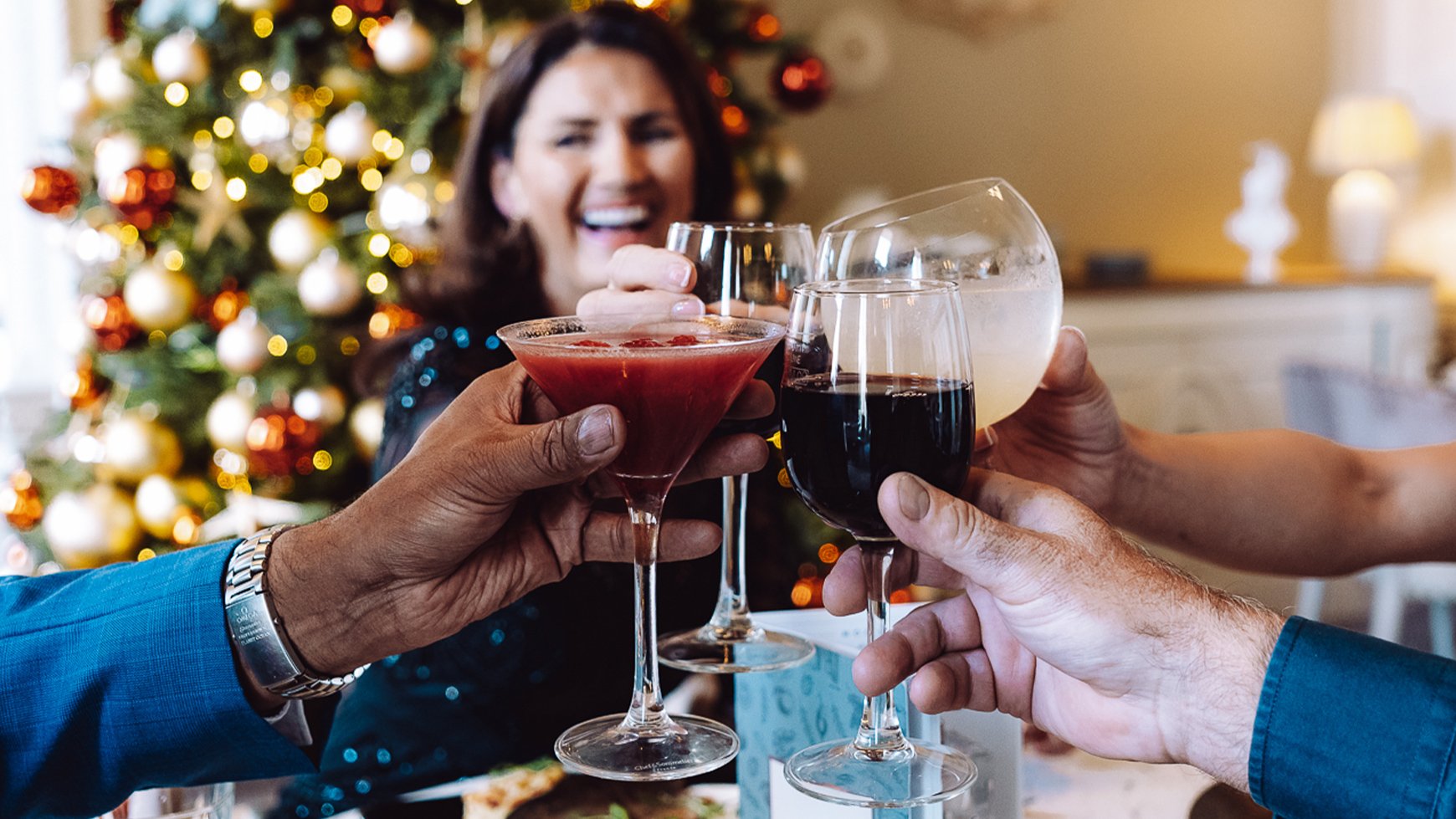 A group of friends make a toast in front of a Christmas tree